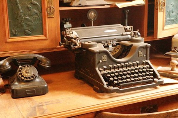 Antique typewriter and telephone on a desk.